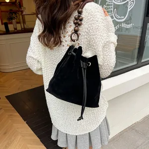 Elegante bolso de ante negro con correa de cuentas de madera vintage en una vista de estilo calle