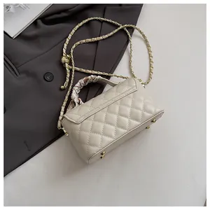 Détail du sac à main beige matelassé avec poignée foulard et bandoulière chaîne dorée