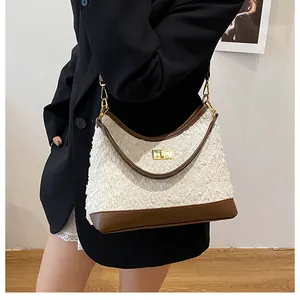 Detalle del bolso de tela boucle blanca con ribete de cuero marrón y cierre metálico dorado