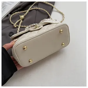 Vue détaillée du fond du sac matelassé beige avec des pieds de protection en métal doré