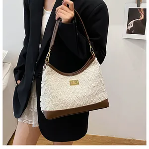 Detalle del bolso de tela bouclé con ribete de cuero marrón y cierre dorado en modelo