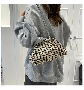 Detalle de bolso bandolera de pata de gallo con cadena plateada sobre sudadera gris