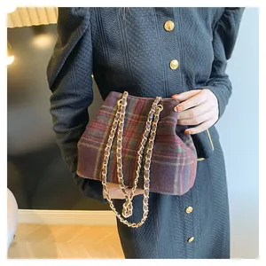 Detail of vintage plaid bucket bag with gold chain strap on a textured black coat