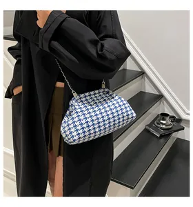 Detalle de bolso nube de pata de gallo azul con cadena plateada sobre abrigo negro
