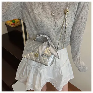Gros plan du sac bandoulière argenté avec poignée en foulard et fermoir doré tournant