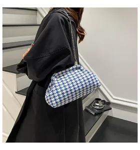Bolso de pata de gallo azul y blanco con cadena plateada y elegante abrigo largo negro