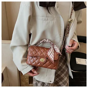 Détail du sac bandoulière matelassé marron avec poignée en foulard et fermoir doré rotatif