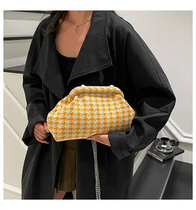Detalle del bolso nube de pata de gallo naranja con cadena de plata sobre abrigo negro