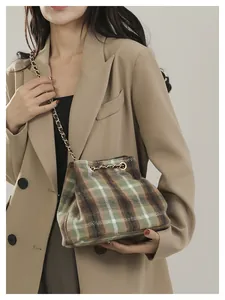Close-up of British retro plaid bucket bag with wool fabric and gold chain strap
