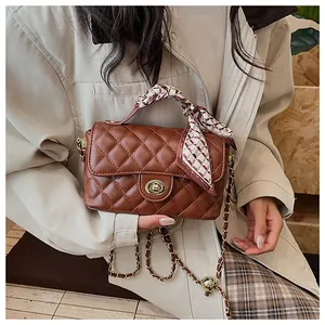 Détail du sac matelassé marron avec fermoir rotatif doré et poignée en foulard de soie