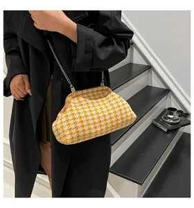 Primer plano de bolso con cadena de pata de gallo naranja usado por una modelo