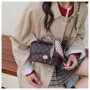 Détail du sac en cuir matelassé marron foncé avec fermoir doré et poignée en soie