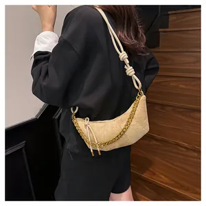 Detalle de bolso medialuna beige con textura mate y elegante cadena metálica dorada