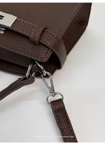 Detalle de piel granulada lichi y herrajes plateados en un bolso bandolera marrón