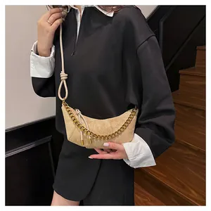Detalle de bolso medialuna de ante beige con cadena dorada y correa con nudos
