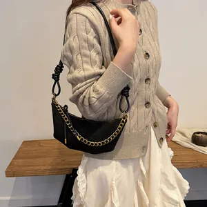 Bolso de media luna negro mate con cadena dorada y correa fina con nudos decorativos