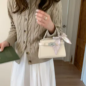 Bolso de mano beige con textura de lichi, pañuelo decorativo y cierre giratorio plateado