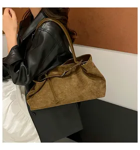 Vista de detalle del bolso de ante marrón grande con correas finas de cuero en una modelo