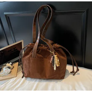 Detalle del bolso tote de ante marrón con cuentas de madera y cierre de cordón