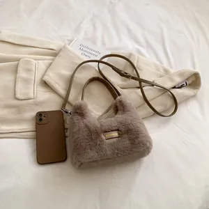 Détail du mini sac à main en fausse fourrure marron avec plaque dorée et bandoulière