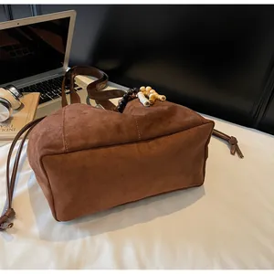 Detalle del bolso tote de ante marrón con adorno de cuentas y asas de cuero