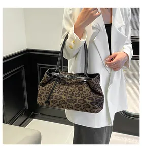 Detalle del bolso tote con estampado de leopardo, correas de cuero negro y hebilla dorada