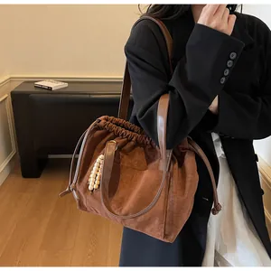Detalle del bolso tote de ante marrón con adorno de cuentas de madera y cordón