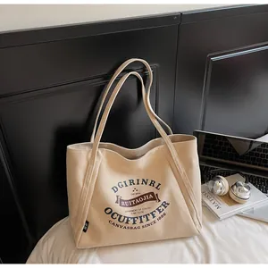 Detalle del bolso tote de lona blanco roto con tipografía retro y textura de tela gruesa