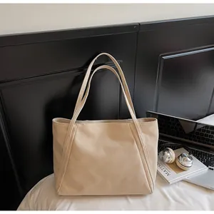 Vista de detalle del bolso tote de lona beige con portátil y libros para un estilo casual