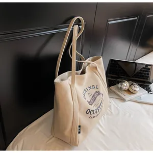 Primer plano de un bolso tote de lona beige con tipografía retro y asas resistentes de moda