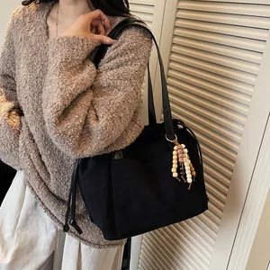 Bolso tote negro retro con textura mate, cierre de cordón y colgante de cuentas chic