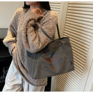 Detalle del bolso tote de lona gris pardo con estampado retro y asas largas