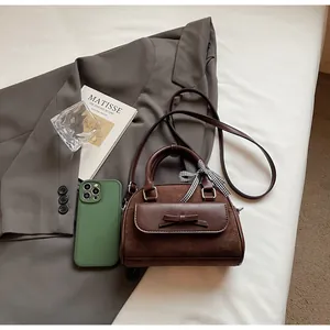Detalle de bolso patchwork de ante marrón oscuro con lazo y cinta de cuadros