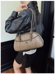 Détail de la texture tressée vintage d'un sac bowling marron avec boucles dorées rétro