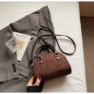 Detalle del bolso tote de ante marrón oscuro con lazo y correa de hombro ajustable
