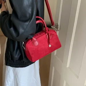 Bolso de mano minimalista en ante rojo con colgante de corazón y correa ajustable
