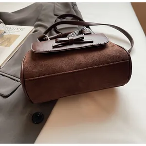 Detalle de bolso de ante marrón con lazo de cuero y asa decorada con pañuelo de cuadros