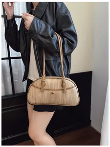 Détail du sac à main tressé avec bordure en cuir marron et fermeture éclair en métal