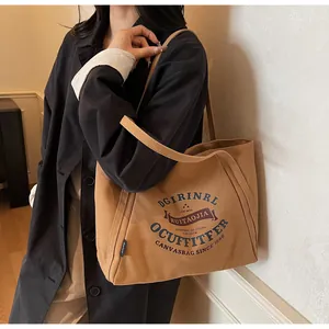 Detalle del estampado de letras vintage y la etiqueta lateral en el bolso tote de lona marrón