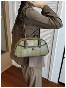 Détail de la texture tissée vert olive et de la boucle dorée du sac à bandoulière chic