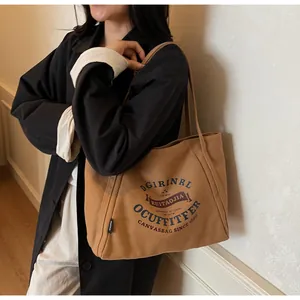 Detalle del bolso de lona con letras de estilo universitario y textura de tela duradera