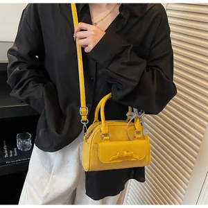 Detalle de un bolso bowling amarillo con lazo decorativo y cinta de seda a cuadros negros