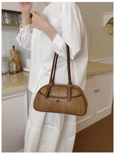 Sac bandoulière marron à texture tissée porté par un mannequin dans un décor chic