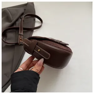 Vista detallada del bolso de silla marrón oscuro con costuras blancas y hebillas doradas