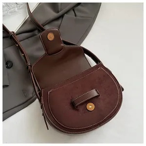Detalle del bolso de silla marrón oscuro con costuras blancas y textura de ante mate
