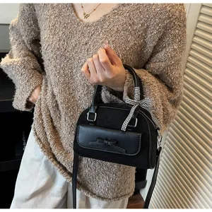 Detalle de bolso de ante con lazo de cuero y cinta de cuadros en el asa superior