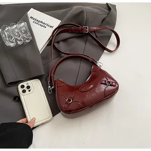 Primer plano detallado del bolso media luna burdeos retro con textura brillante y aros de metal