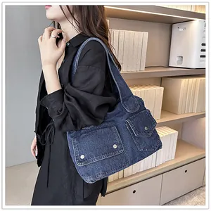 Detail der blauen Denim-Tragetasche mit funktionellen Klappentaschen und Metallschnalle