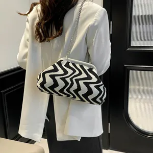 Chic black and white wavy pattern knit shell bag with silver chain on a white blazer