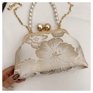 Close-up of elegant floral embroidery and pearl handle detail on a vintage shell bag